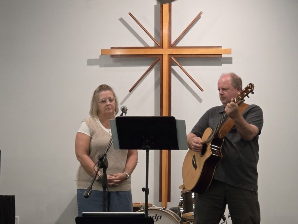 Rock & Refuge musicians leading worship beneath the sanctuary cross